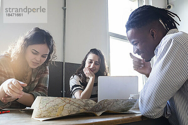 Lächelnde Geschäftsleute diskutieren am Tisch im Büro