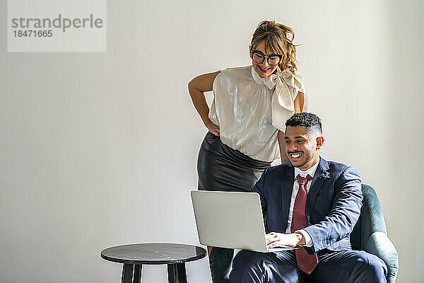 Happy businessman sharing laptop with colleague