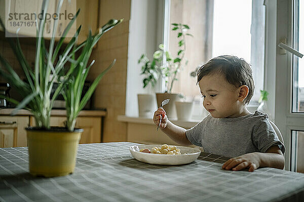 Junge isst Nudeln am Tisch zu Hause