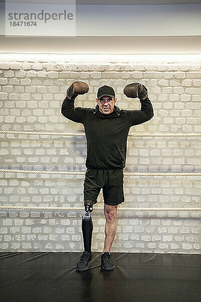 Selbstbewusster Mann mit künstlichen Gliedmaßen  der im Fitnessstudio Muskeln spielen lässt