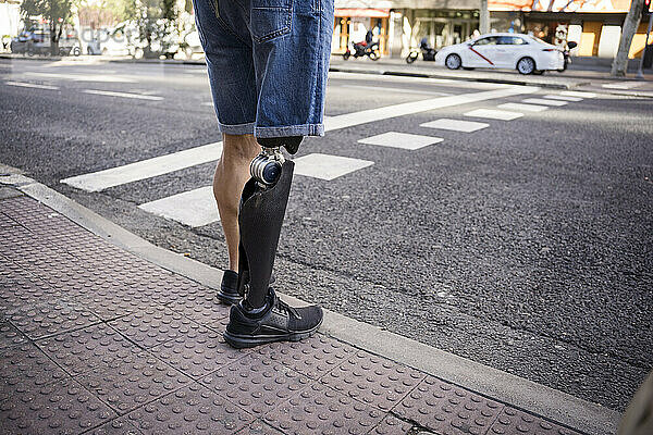 Mann mit Beinprothese wartet am Straßenrand