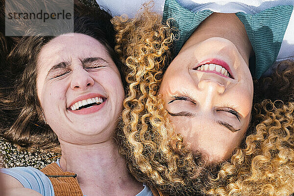 Friends lying next to each other laughing happily