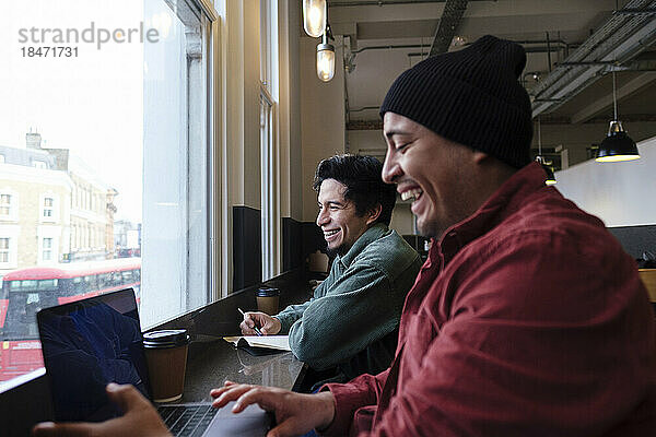 Happy freelancers with laptop working together in cafe