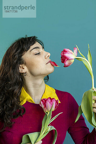 Frau mit Tulpenblatt im Mund vor grünem Hintergrund