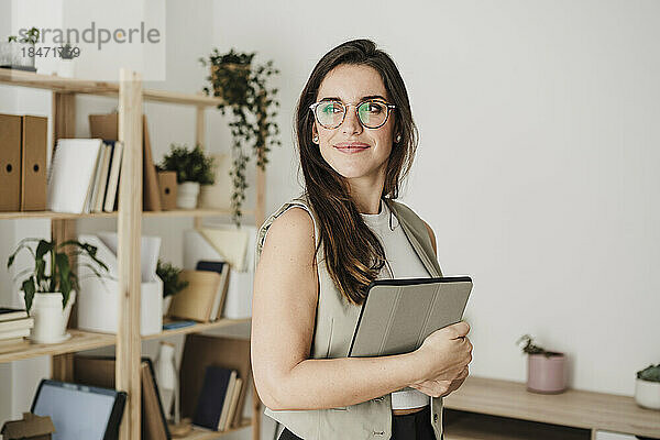 Nachdenkliche Geschäftsfrau mit Brille steht im Büro