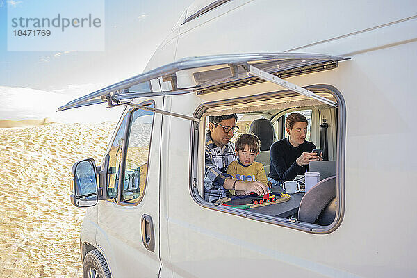 Sohn spielt an sonnigem Tag mit Vater im Wohnmobil in der Wüste