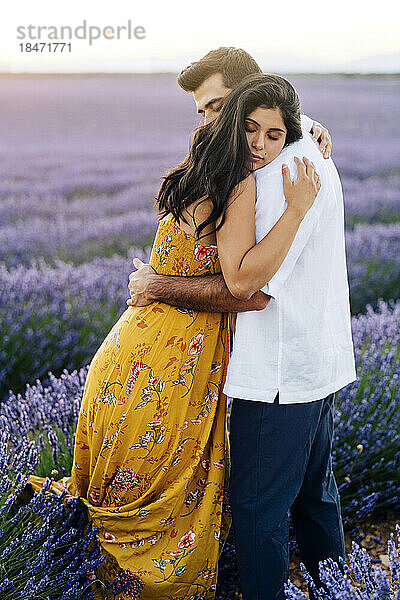 Young woman hugging man standing at lavender field