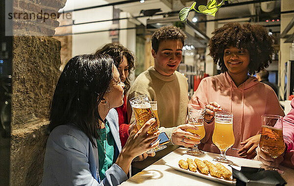 Glückliche junge Freunde  die Bier auf einer Dinnerparty genießen