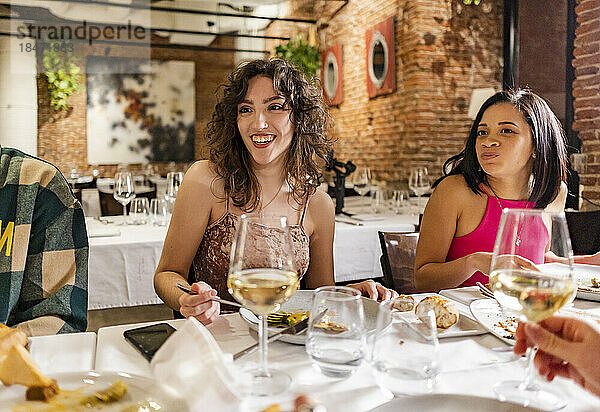 Glückliche Frauen genießen das Abendessen mit Freunden im Restaurant