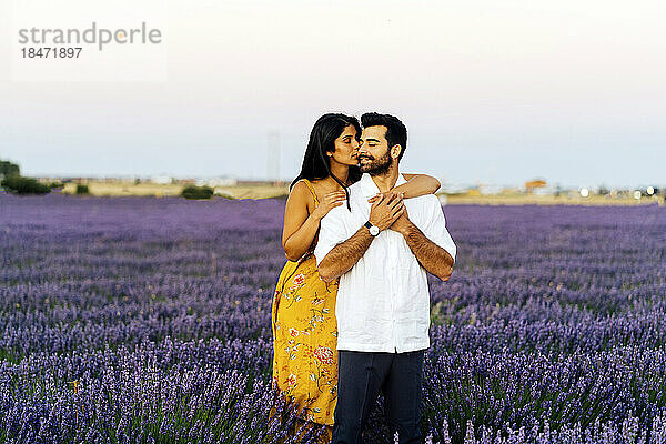 Young woman embracing man in lavender field under sky