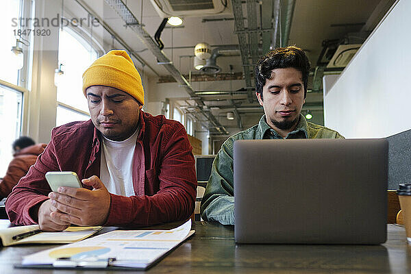 Freiberufler arbeiten am Laptop und nutzen Smartphone im Café