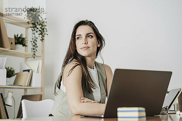 Nachdenkliche Geschäftsfrau sitzt mit Laptop im Büro