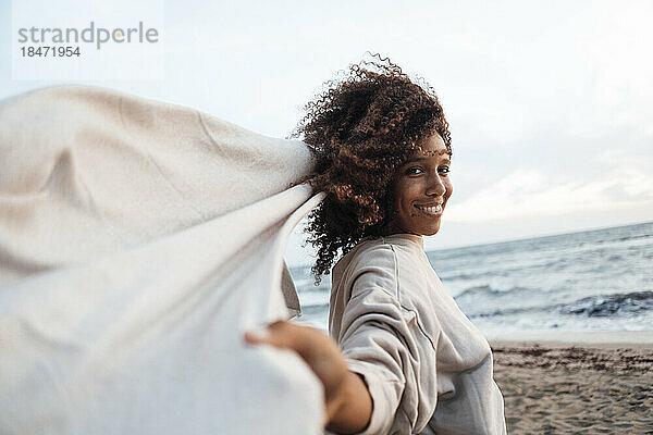 Glückliche Frau mit Schal am Strand