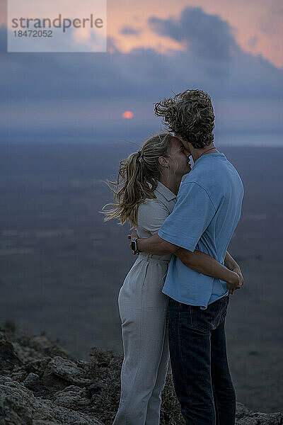 Romantische Frau umarmt ihren Freund bei Sonnenuntergang