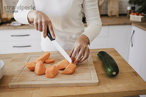 Hände einer Frau  die zu Hause in der Küche Gemüse schneidet