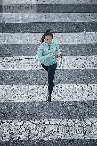 Junge Frau joggt auf Zebrastreifen