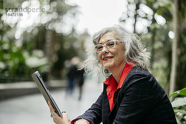 Nachdenklich lächelnde Geschäftsfrau mit Tablet-PC