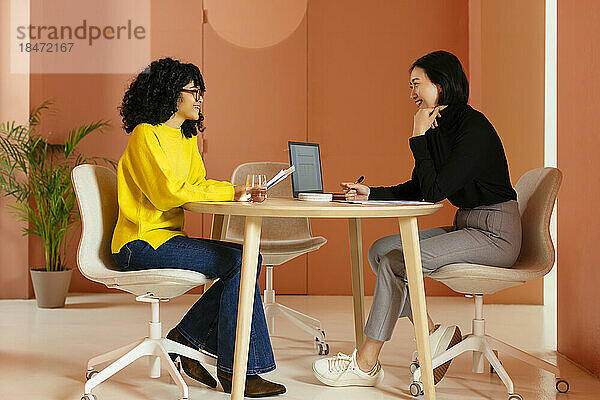 Lächelnde Geschäftsfrauen  die am Schreibtisch im Büro zusammenarbeiten