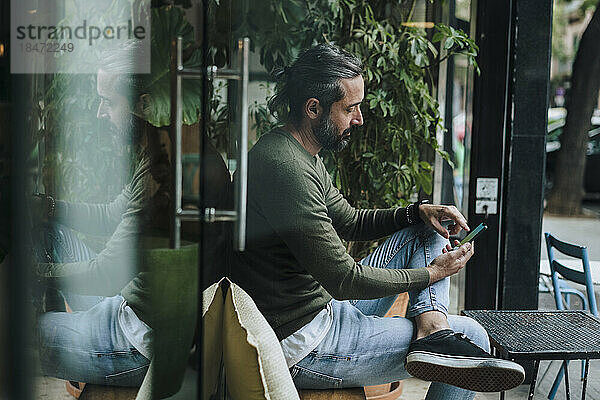 Bärtiger Mann benutzt Smartphone im Café