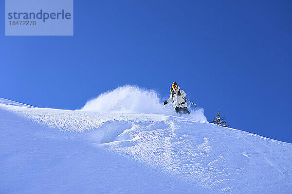 Reife Frau fährt unter blauem Himmel Ski