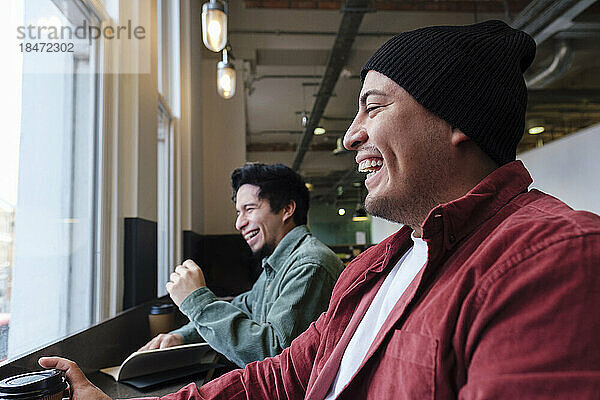 Cheerful freelancers laughing together sitting in cafe