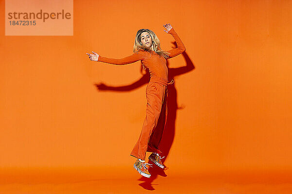Frau schwebt vor orangefarbenem Hintergrund