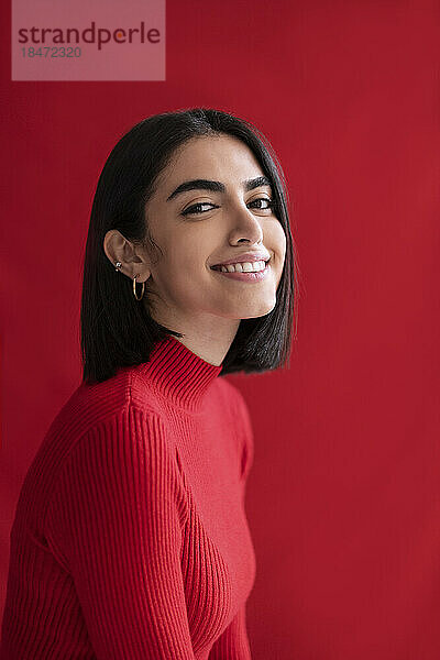Lächelnde junge Frau vor rotem Hintergrund