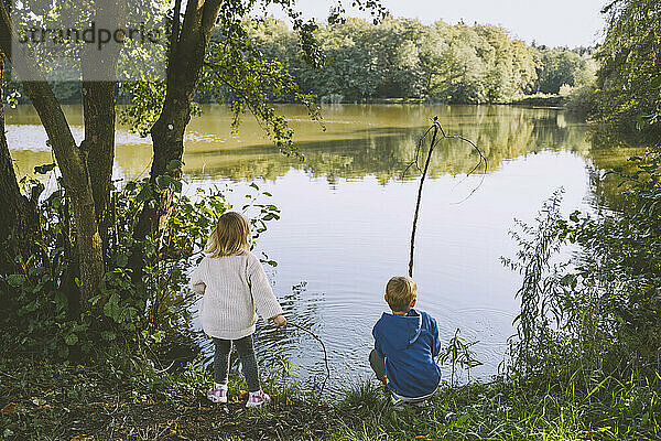 Junge spielt mit Mädchen in der Nähe eines Sees