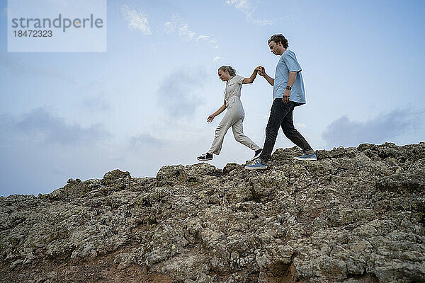Junges Paar geht miteinander auf einem felsigen Berg spazieren
