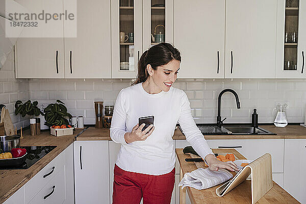 Glückliche Frau benutzt Tablet-PC in der Küche