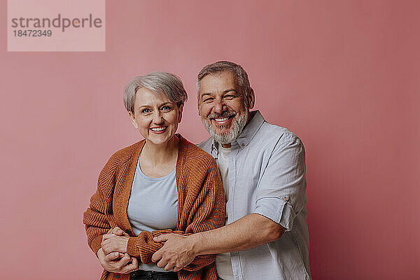 Mature man and woman against pink background