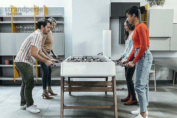 Geschäftskollegen spielen gemeinsam Tischfußball im Büro