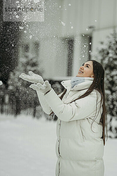 Frau hat Spaß beim Spielen mit Schnee im Winter