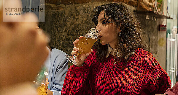 Junge Frau trinkt Bier im Restaurant