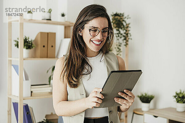 Glückliche Geschäftsfrau mit Tablet-Computer im Büro