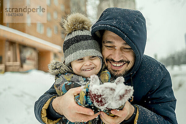 Father and son wearing warm clothing enjoying together in snow