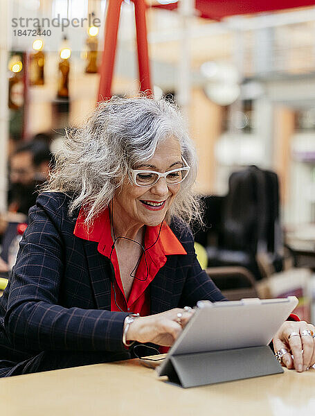 Lächelnde Geschäftsfrau benutzt Tablet-PC im Café