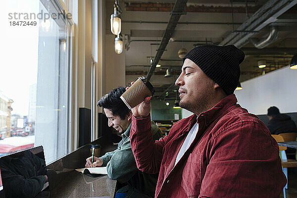 Freiberufler trinkt Kaffee mit Bruder  der im Café sitzt