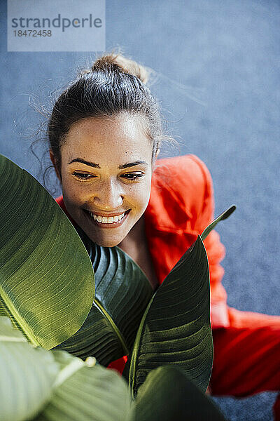 Happy businesswoman with plant sitting in office