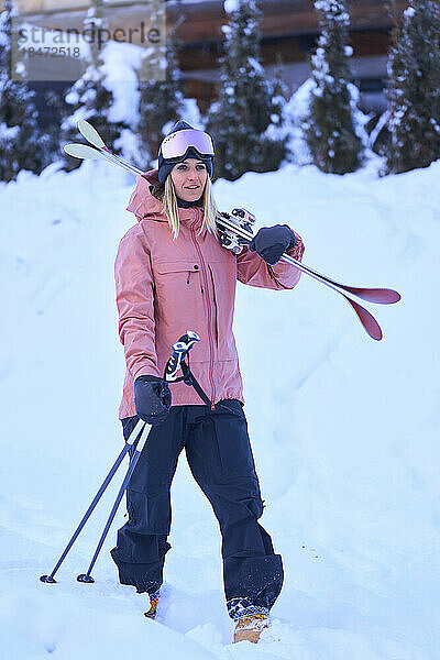Frau mit Skiern und Skistöcken steht im Schnee