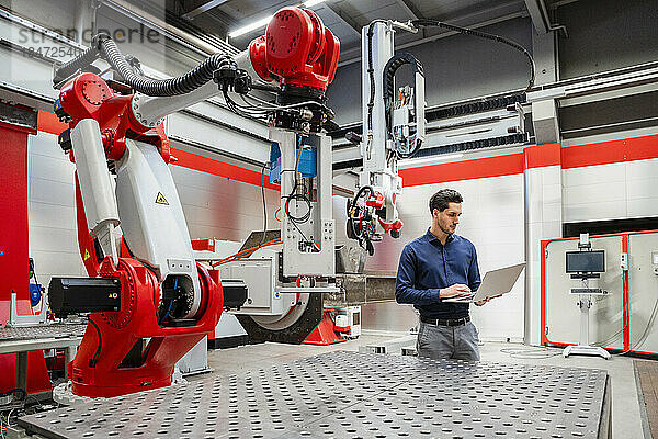 Ingenieur benutzt Laptop in Roboterfabrik