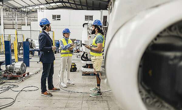 Ingenieure mit Schutzhelm diskutieren in der Fabrik