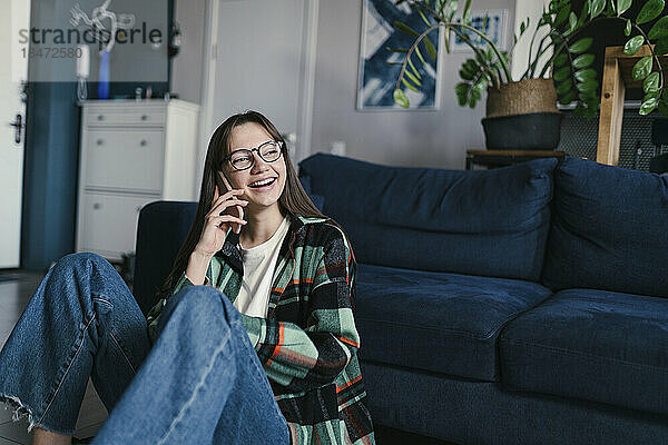 Glückliche junge Frau  die zu Hause mit dem Smartphone spricht