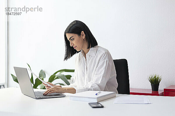 Geschäftsfrau tippt Dokumente auf Laptop am Schreibtisch