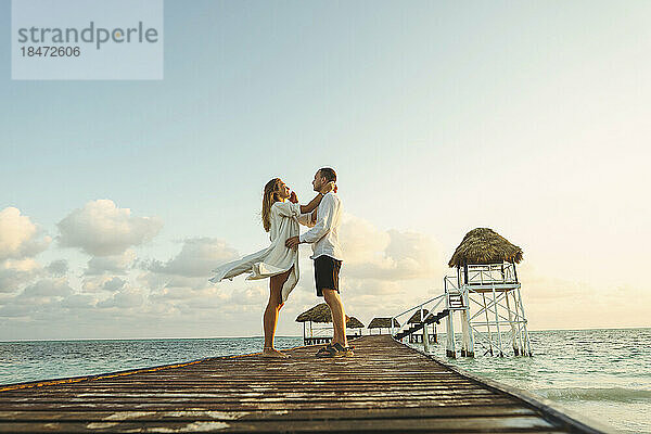 Romantisches junges Paar steht auf einem Pier inmitten des Meeres