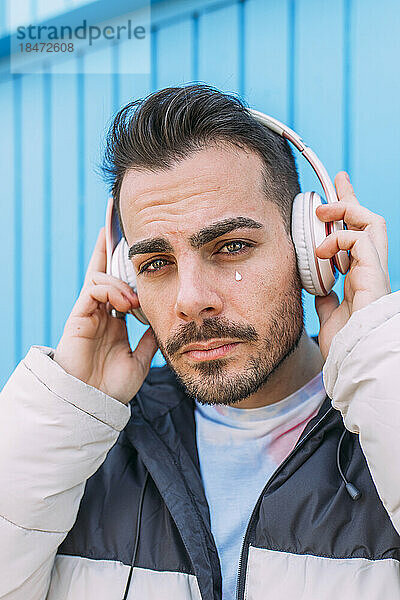 Junger Mann trägt kabellose Bluetooth-Kopfhörer