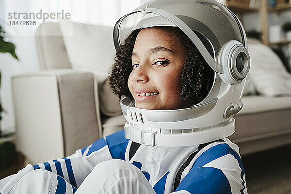 Lächelndes Mädchen mit Weltraumhelm zu Hause