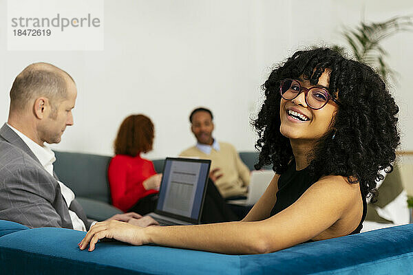 Junge Geschäftsfrau mit Afro-Frisur sitzt mit Kollegin im Büro