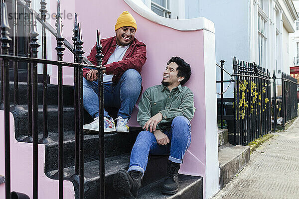 Lächelnde Brüder sitzen zusammen auf Stufen