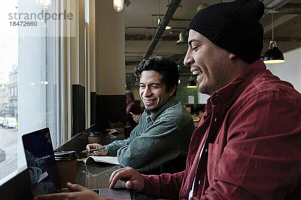 Happy freelancers using laptop in cafe